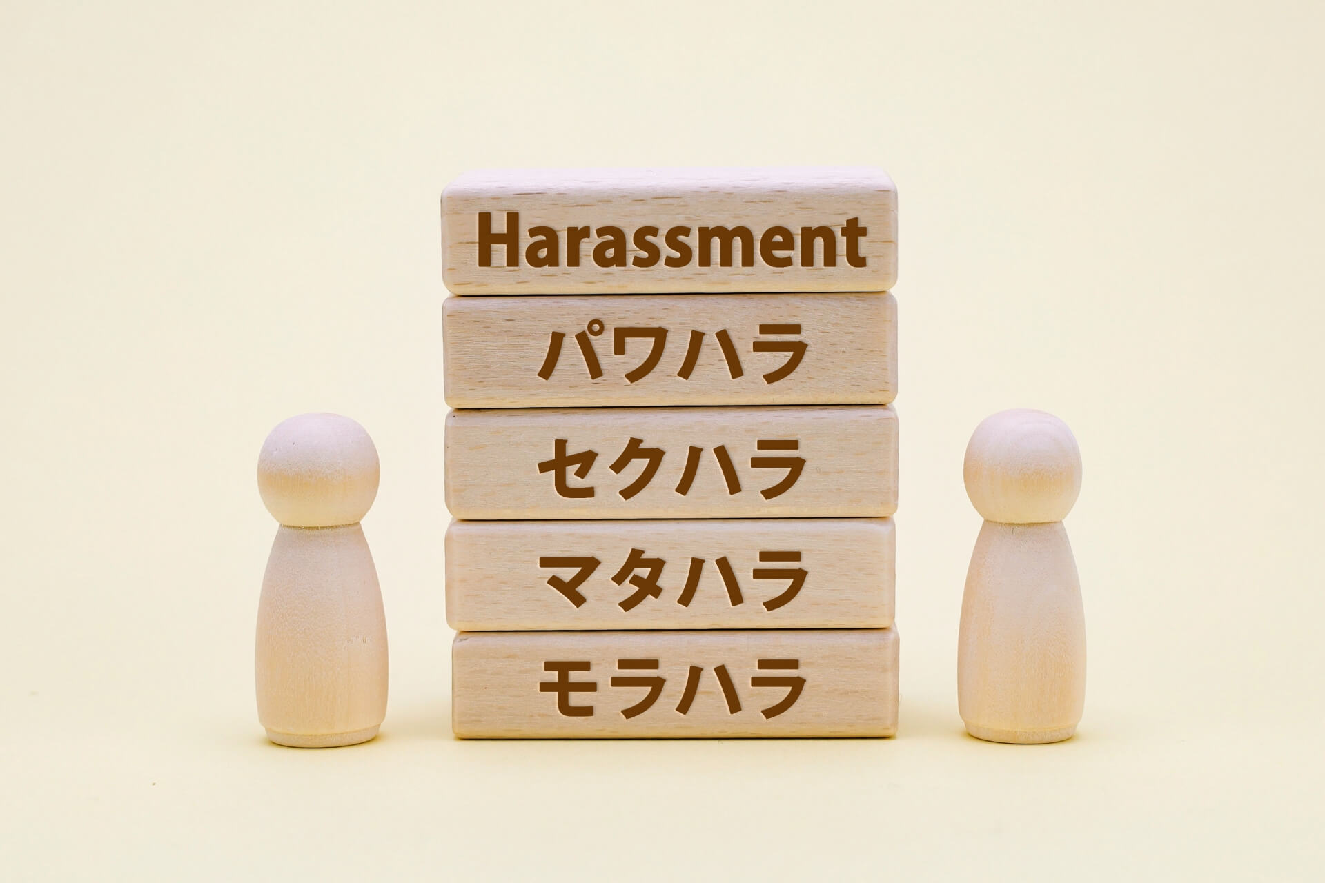 さまざまなハラスメントの種類が書かれた積み木と人形 (1)
