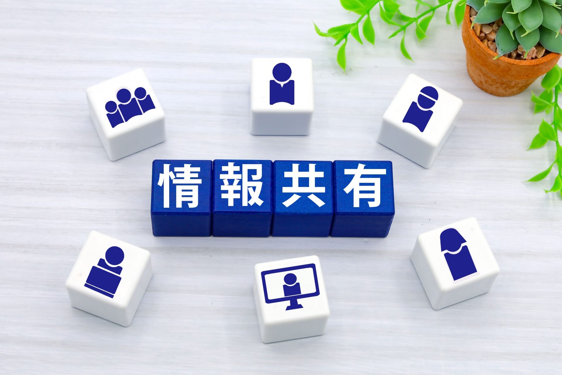 ブロックで表された「情報共有」と社員のアイコン。報連相や情報共有を仕組み化することの重要性を示唆する画像。