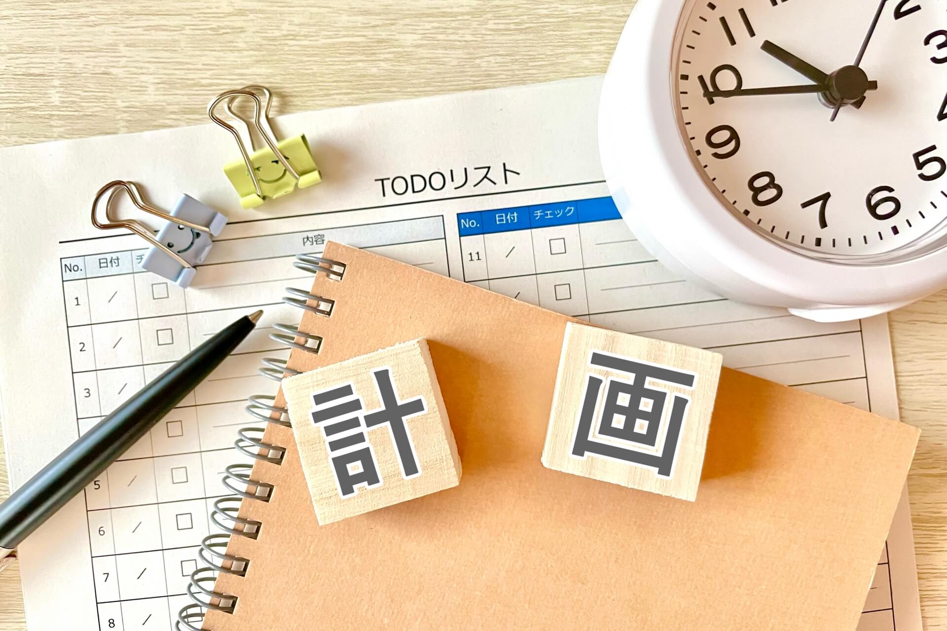 「計画」と書かれた木のブロック、TODOリスト、時計、ペンが置かれた、計画策定をイメージさせるデスク風景。
