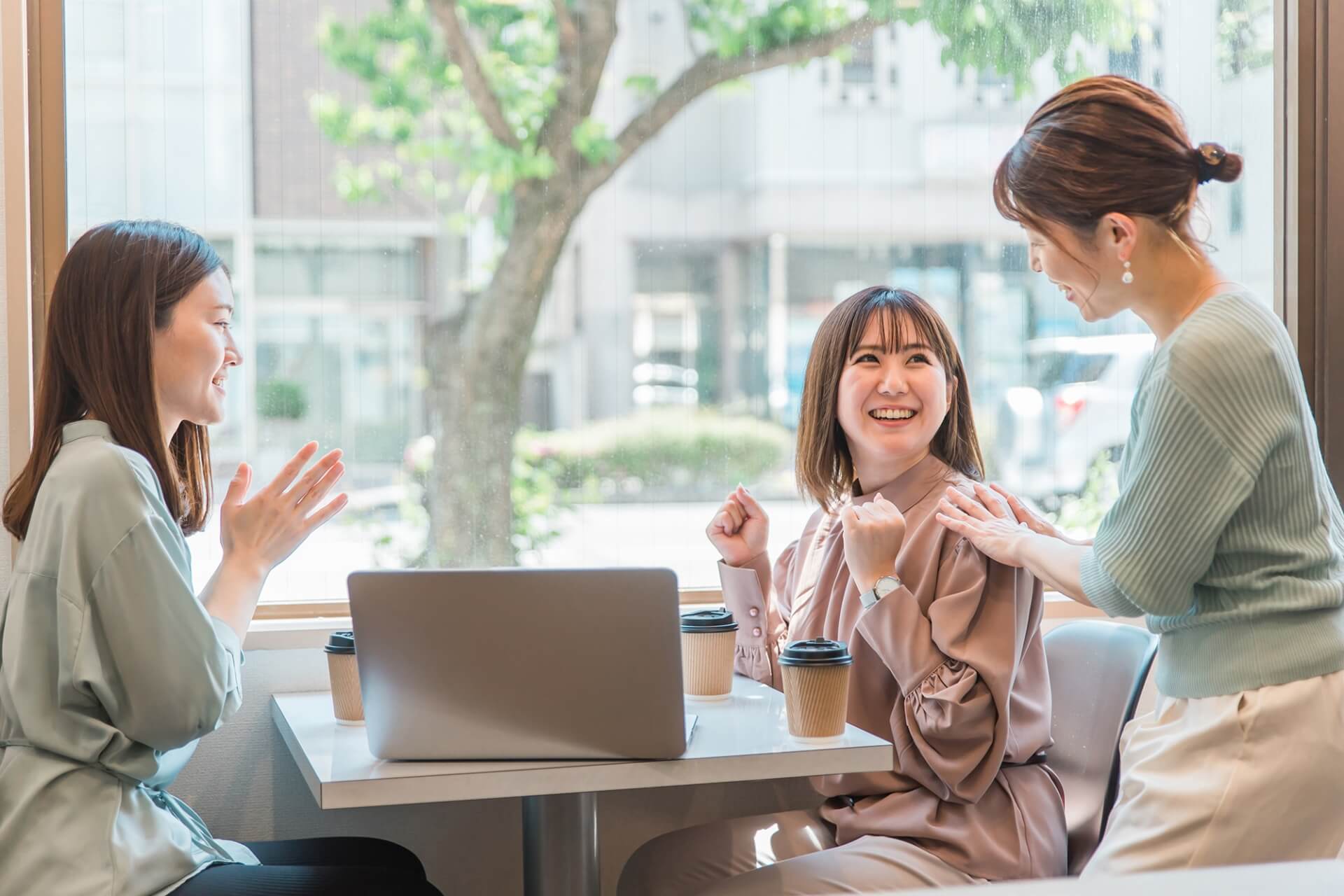 窓際の明るいオフィスで賞賛を受ける女性社員