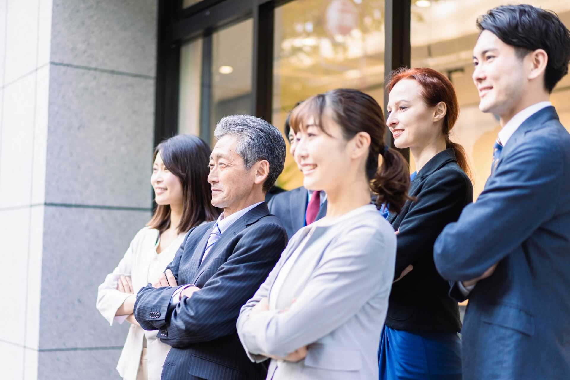 笑顔で同じ方向を見つめる多様な世代のビジネスパーソン男女のグループ