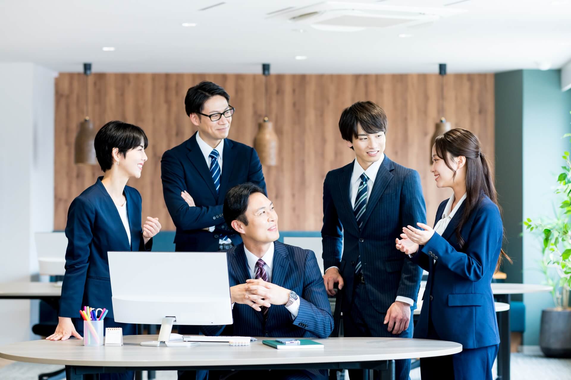 明るいオフィスで笑顔で話し合う、主体性を持ったビジネスチームの様子